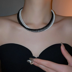 Detail of multi-layered beaded necklace with black, white, and grey beads on neck