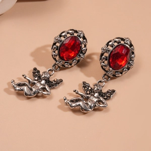 Detail view of retro silver earrings with red oval gemstones and angel charms