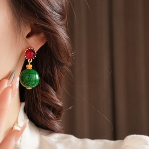 Gros plan de boucles d'oreilles vintage en céramique avec clous rouges et perles vertes