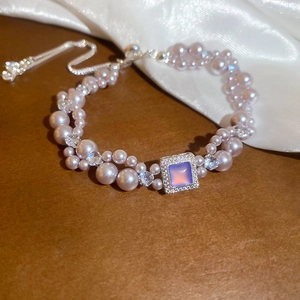 Gros plan d'un bracelet en perles roses avec pierre bleue et zircons sur soie