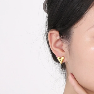 Minimalist 18k gold heart stud earrings shown on model for a trendy fashion look