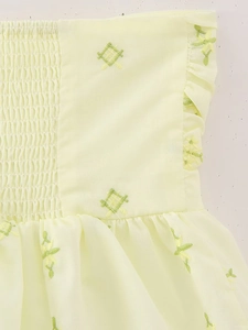 Détail du haut en coton jaune avec broderie florale verte délicate et texture smockée