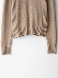 Detail of ribbed hem and cuffs on earth-toned knit sweater with fine flat stitch texture