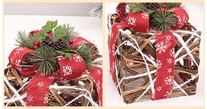 Detail of rattan Christmas gift box with pine cones and red burlap ribbon decor