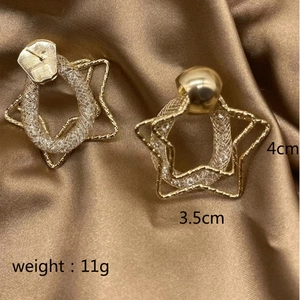 Detail view of 4cm gold star earrings with chain link texture on brown silk
