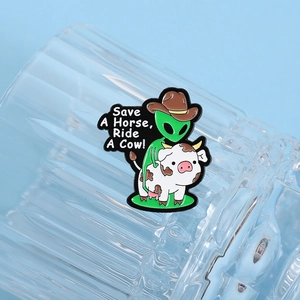Detail of alien pin on a glass with Save A Horse Ride A Cow text and cowboy hat