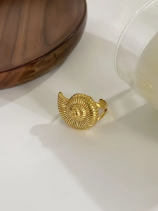Detail of vintage golden spiral conch shell ring with hollowed design on white background