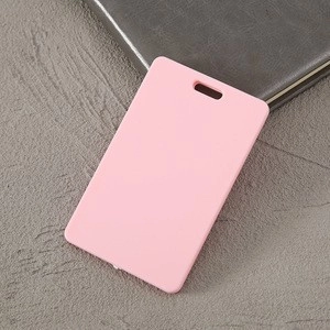 Pink ABS plastic ID card holder on a textured surface next to a dark notebook