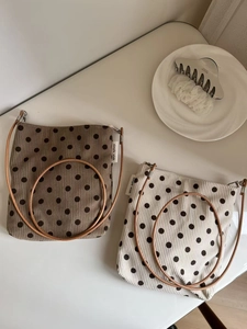 Detailed view of polka dot corduroy crossbody bags with leather straps and logo tags