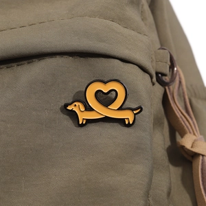 Broche en émail de teckel en forme de cœur sur un sac en toile vert olive rustique