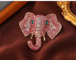 Close-up of pink rhinestone elephant brooch with gold accents on brown satin background