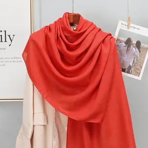 Detail of solid red linen scarf draped over a beige blazer for a stylish seasonal look