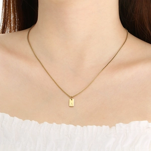 Golden rectangular pendant necklace with engraved letter A shown on a female model
