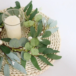 Detail of eucalyptus wreath with white pearls, glass candle holder and woven mat