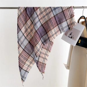 Close-up of a purple and blue plaid scarf with fringes hanging on a metal rack