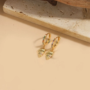 Detailed close-up of gold shell pendant earrings with colorful zircon inlay on stone