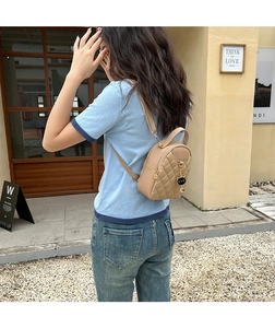 Detail of quilted apricot mini backpack featuring a gold cat charm and PU leather texture