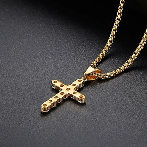 Detailed macro view of golden hip hop cross pendant with micro-set zircon on box chain