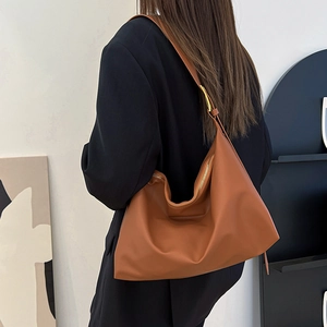 Brown large capacity leather tote bag worn by model in a minimalist indoor setting