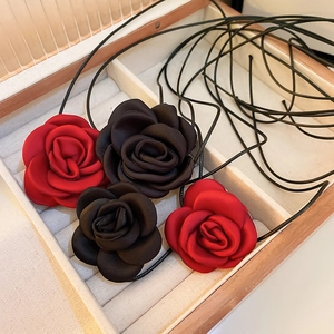 Detailed macro view of handmade fabric rose necklaces in red and black inside a wooden jewelry box