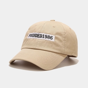 Detail of khaki cotton baseball cap with white 1986 embroidery and reinforced stitching