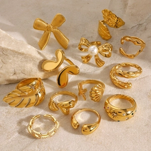 Set of 10 gold stainless steel rings with pearl and leaf designs on marble background