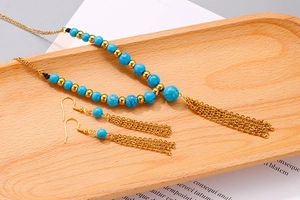 Dettaglio di un set gioielli boho con perline turchesi e nappe dorate su legno