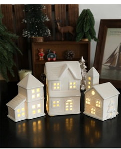 Close-up of three white ceramic glowing houses with warm lights for Nordic Xmas decor