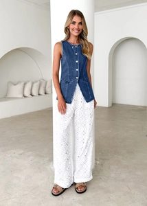 Sleeveless denim vest and white wide-leg pants styled in a minimalist studio setting