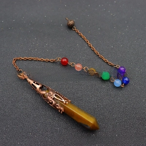Detailed shot of tiger eye stone crystal pendulum with seven chakra healing beads