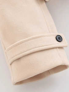 Detailed macro view of beige wool coat cuffs with textured fabric and black button detail