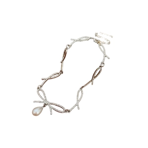 Silver bow necklace with sparkling crystals and a drop pearl pendant on white background