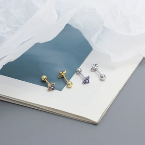 Macro shot of gold and silver four-leaf clover stud earrings with purple zircons