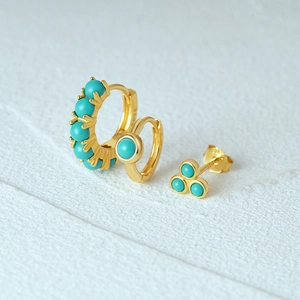 Macro detail of gold S925 silver earring set with turquoise stones on white background