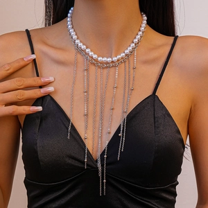 Close-up of double-layer necklace with white pearls and silver tassel chains on a model