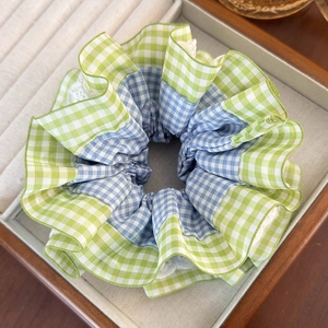 Macro view of blue plaid hair scrunchie with layered lace edges in a jewelry box