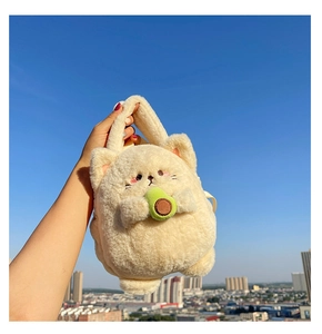 Close-up of a plush cat bag with avocado detail held against a bright blue sky background