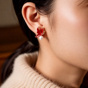 Gros plan de boucles d'oreilles papillon rouges avec perles blanches sur l'oreille