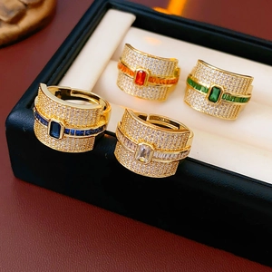Close-up of four luxury gold rings with colorful square zircons on a white velvet display