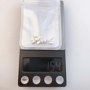 Close-up of baroque pearl nail charms on a digital scale showing 1.54 grams weight