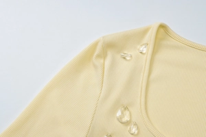 Primo piano di un top in maglia a coste giallo con eleganti decorazioni a goccia di cristallo