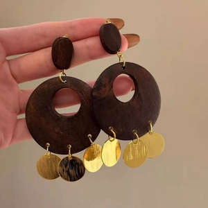 Detail of retro wooden earrings with brown circles and dangling gold sequins