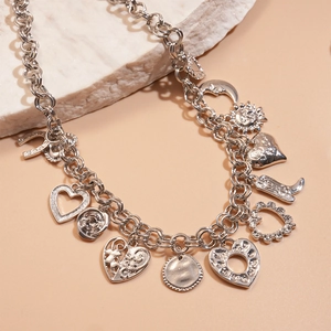 Detailed shot of silver charm necklace with star, moon and heart pendants on stone