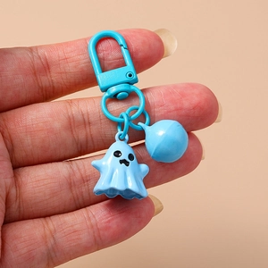Cute blue ghost keychain with matching bell and hook accessory in minimalist hand display