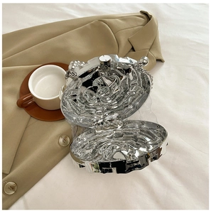 Detail of silver shell-shaped evening bag with liquid metal texture on a blazer