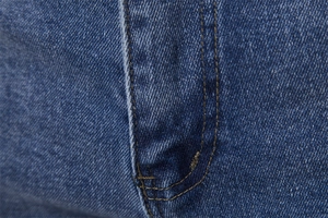 Macro detail of mid-blue twill denim fabric showing stitching and high-quality texture