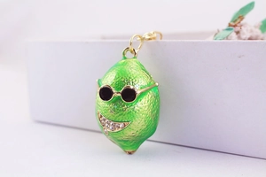 Dettaglio macro di un ciondolo a limone verde con occhiali da sole e strass lucidi