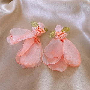 Close-up of pink fabric petal earrings with bead clusters and green leaf details