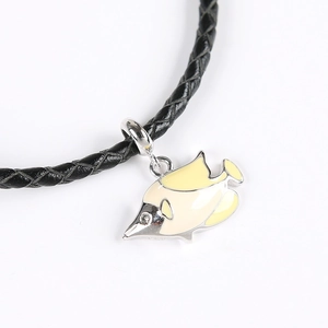 Détail d'un pendentif poisson jaune émaillé avec strass sur un cordon en cuir noir