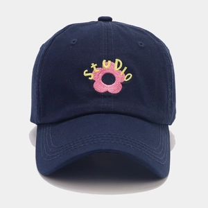Detail of pink flower embroidery and yellow STUDIO text on navy cotton baseball cap